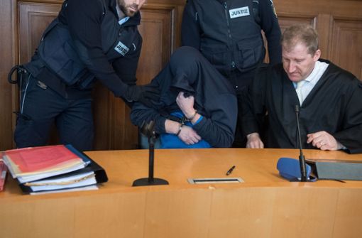 Der Angeklagte zieht sich seine Jacke über sein Gesicht. Foto: dpa