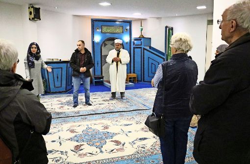 Betül Sahin, Beba Hadis und der Imam (von links) zeigen den  Besuchern den mit Teppichen ausgelegten Gebetsraum. Foto: Eva Herschmann