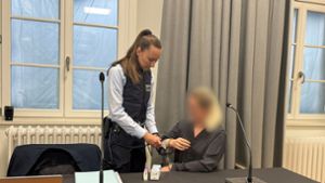 Eine Justizmitarbeiterin nimmt der Angeklagten beim Prozessauftakt vor dem Landgericht Ravensburg die Handschellen ab. Foto: Aleksandra Bakmaz/dpa