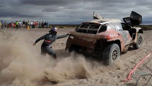 Peugeot-Fahrer Cyril Despres schiebt sein Auto an. Die Rallye Dakar ist brandgefährlich – und sie produziert spektakuläre Bilder. Eine Auswahl der Rallye 2016 zeigen wir in der folgenden Fotostrecke. Foto: AP