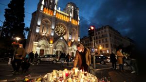 Eine Frau zündet eine Kerze vor der Basilika in Nizza an, wo am 29. Oktober eine Messerattacke stattfand. Foto: dpa/Valery Hache