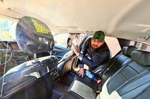 Markus Diler von Funk-Taxi Schoch säubert die Scheibe, die  Fahrer und Fahrgast vor einer Ansteckung schützen soll. Foto: Patricia Sigerist