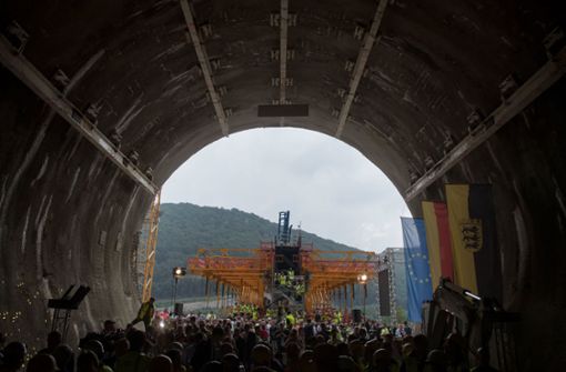 Tunnelarbeiter und Besucher der Durchschlagsfeier stehen nach dem Durchschlag im Boßlertunnel, im Hintergrund ist ein Gerüst der sich im Bau befindlichen Filstalbrücke zu sehen. Foto: dpa