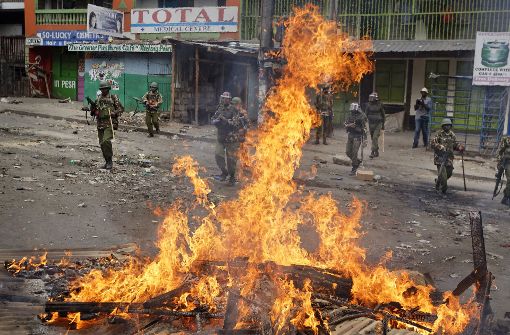Polizisten stehen in einem Slum in Nairobi vor einer brennenden Barrikade. Foto: AP