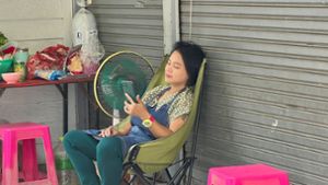 Im Schatten und mit Ventilator: Eine Frau in Bangkok versucht, sich sich abzukühlen. Foto: Carola Frentzen/dpa