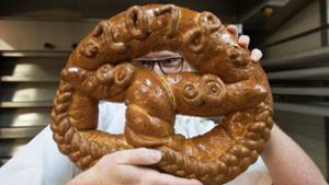 Optimistischer Blick ins neue Jahr: ein Bäcker aus Freiburg im Breisgau präsentiert  eine seiner Brezeln, die er für den Neujahrstag 2018 gebacken hat. Foto: dpa