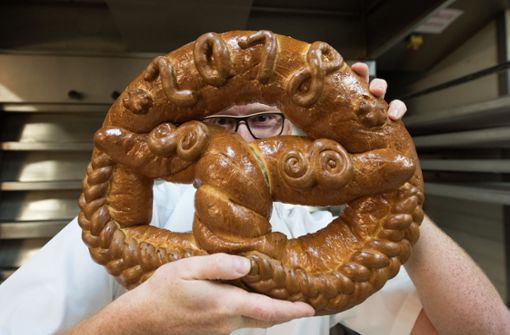 Optimistischer Blick ins neue Jahr: ein Bäcker aus Freiburg im Breisgau präsentiert  eine seiner Brezeln, die er für den Neujahrstag 2018 gebacken hat. Foto: dpa