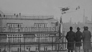 Ein Fotograf hält das waghalsige Luftmanöver von Jules Védrines am 19. Januar 1919 mitten in Paris mit seiner Kamera für die Nachwelt fest. Foto: Wikipedia commons/Inconnu/BM Reims