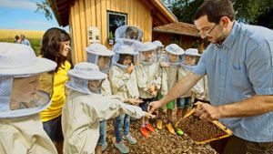 Der Imker André Riehle zeigt Grundschülern vor dem Bienenhaus, dass sie keine Angst vor den Insekten  haben müssen. Foto: Michael Steinert