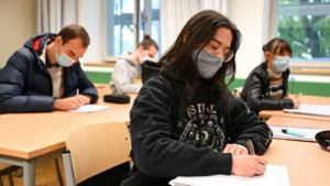 Schüler des Spohn-Gymnasiums in Ravensburg sitzen bei geöffnetem Fenster mit Mund- und Nasenschutz im Unterricht. Foto: dpa/Felix Kästle