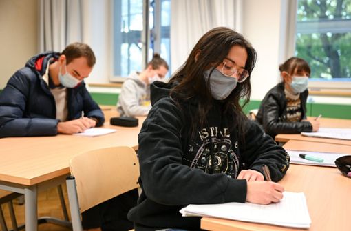 Schüler des Spohn-Gymnasiums in Ravensburg sitzen bei geöffnetem Fenster mit Mund- und Nasenschutz im Unterricht. Foto: dpa/Felix Kästle