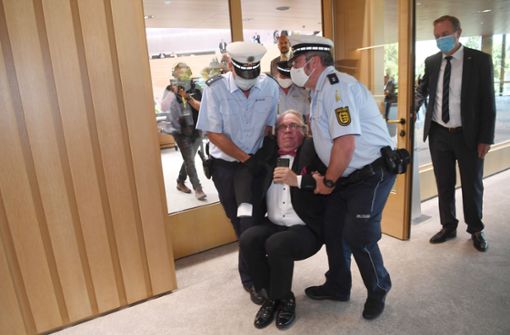 Der Ex-AfD-Abgeordnete Heinrich Fiechtner wird im Juni 2020 von Polizisten aus dem baden-württembergischen Landtag getragen. Zuvor wurde er von der Sitzung ausgeschlossen, hatte sich aber geweigert  zu gehen. Foto: dpa/Marijan Murat