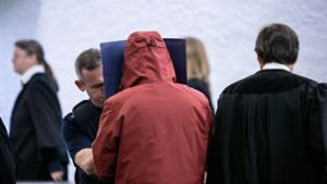 Der Angeklagte schützt sich beim Betreten des Saals vor den Blicken der Zuschauer. Foto: Lichtgut/Julian Rettig