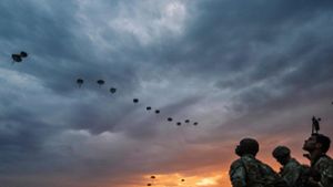 Am Himmel ziehen Transportflugzeuge vorbei,  wie an einer unsichtbaren Schnur ziehen sie Seidenpilze hinter sich her – der Auftrag der Fallschirmjäger: Die feindlichen Kräfte im Rücken anzugreifen. Foto: AFP
