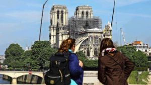 Zwei Frauen betrachten in Paris die bei einem Brand schwer geschädigte Kathedrale von Notre-Dame. Foto: AFP