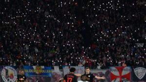 Die Zuschauer im Stadion lassen in Gedenken an einen gestorbenen Fan die Lichter ihrer Handys leuchten. Foto: Robert Michael/dpa