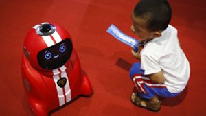Wer lernt hier von wem? Ein Kind beobachtet während der Welt-Roboter-Konferenz in Peking (China) einen selbstlernenden Roboter. Foto: AP