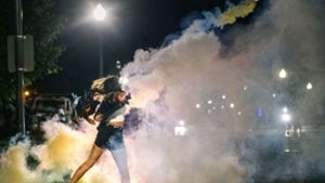 Proteste und Ausschreitungen in Wisconsin: Eine Demonstrantin schmeißt eine Dose mit Tränengas zurück. Foto: AFP/Brandon Bell