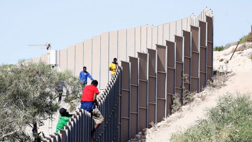 Migranten klettern über einen Zaun auf der italienischen Insel Lampedusa. Foto: Cecilia Fabiano/LaPresse via ZUMA Press/dpa
