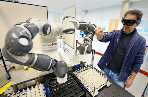 Ein Bosch-Mitarbeiter interagiert im Robotiklabor am Forschungsstandort Renningen mit einem  Fertigungsroboter. Foto: dpa/Franziska Kraufmann