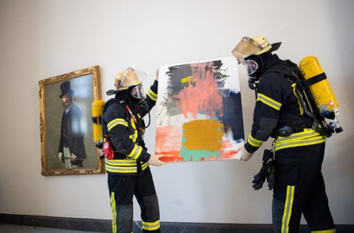 Feuerwehrleute tragen ein Kunstwerk aus dem Altbau der Staatsgalerie Stuttgart. Foto: dpa/Tom Weller