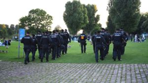 Polizeibeamte gehen in Heidelberg über die  Neckarwiese. Foto: dpa/Rene Priebe