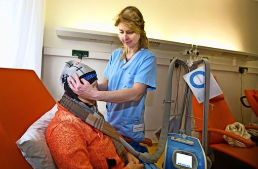 Teamleiterin Liebetraut Paprotta setzt einer Patientin die Haube auf. Über dem blauen Kühlmodul ist  noch eine Isolierung. Foto: Ines Rudel