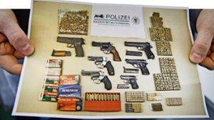 Ein Polizist zeigt, was die Kollegen in Baden-Württemberg an Waffen und Munition beschlagnahmt haben. Foto: dpa