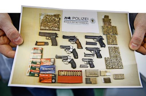 Ein Polizist zeigt, was die Kollegen in Baden-Württemberg an Waffen und Munition beschlagnahmt haben. Foto: dpa
