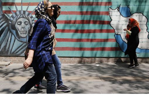 Drei Iranerinnen  gehen an Wandmalereien an der Wand der ehemaligen US-Botschaft in der Hauptstadt Teheran vorbei. Foto: AFP