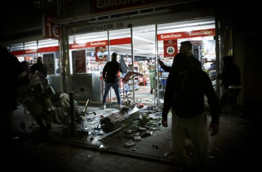Die Krawallnacht in Stuttgart: Menschen stehen vor einem geplünderten Geschäft in der Marienstraße.  Nun sollen fünf weitere Sozialarbeiter dabei helfen, eine erneute Krawallnacht zu verhindern. Foto: dpa/Julian Rettig
