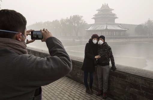 Bitte recht freundlich, auch wenn man von der Verbotenen Stadt im Hintergrund herzlich wenig erkennen kann. Die Luftverschmutzung in Peking hat unglaubliche Höchstwerte erreicht. Foto: Getty Images