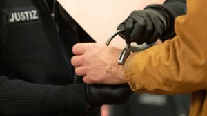 Ein Justizbeamter schließt dem Angeklagten Handschellen auf in einem Saal vom Landgericht (Symbolbild). Foto: Friso Gentsch/dpa