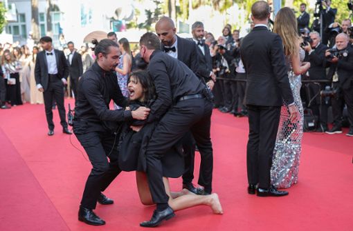 Eine Frau stürmte während einer Premiere bei den Filmfestspielen zwischen die Gäste. Sicherheitspersonal musste eingreifen. Foto: AFP/VALERY HACHE
