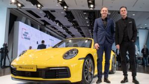 Oliver Blume, Vorstandsvorsitzender der Porsche AG (l.) und Lutz Meschke, Finanzvorstand der Porsche AG, posieren vor der Bilanz-Pressekonferenz vor einem Porsche 911 Carrera 4S Cabrio. Foto: dpa
