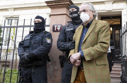Bei einer Razzia gegen sogenannte Reichsbürger führen vermummte Polizisten nach der Durchsuchung eines Hauses in Frankfurt am Main Heinrich XIII. Prinz Reuß (rechts) zu einem Polizeifahrzeug. Foto: dpa/Boris Roessler