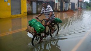 Mit Kraft voran: Durch überflutete Straßen kämpft sich ein Mann auf seinem Fahrrad. Seit der Nacht zu Samstag verwüsteten schwere Unwetter und starke Regenfälle den Südosten Brasiliens, mindestens 23 Personen kamen ums Leben. Foto: Bruna Prado/AP/dpa