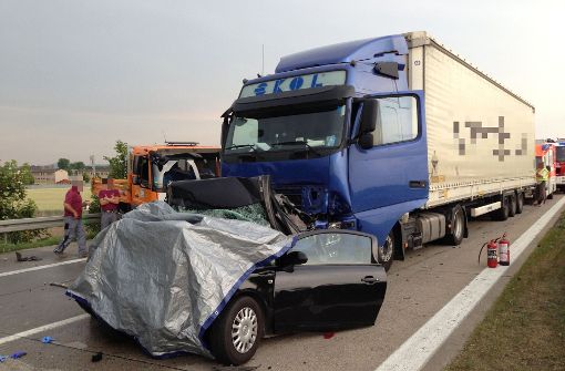 Mit einer Plane abgedeckt ist ein Personenwagen, auf den auf der Autobahn A 6 bei Viernheim (Hessen) am 12. Juni 2015 am Stauende ein Lastwagen gefahren war. Foto: dpa