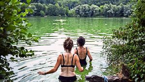 Zwei Frauen gehen bei hochsommerlichen Temperaturen am Baggersee in Kirchentellinsfurt (Baden-Württemberg) baden Foto: dpa