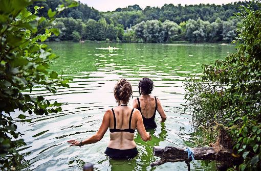 Zwei Frauen gehen bei hochsommerlichen Temperaturen am Baggersee in Kirchentellinsfurt (Baden-Württemberg) baden Foto: dpa