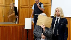 Die Angeklagte betritt  den Gerichtssaal und verbirgt ihr Gesicht hinter einem großen Briefumschlag. Foto: dpa