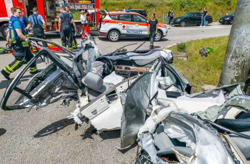 Helfer stehen nach einem Verkehrsunfall hinter dem Wrack eines Autos auf einer Landstraße. Foto: Julian Buchner/Einsatz-Report24/