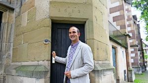 Pfarrer Florian Link am Turmeingang. Links neben der Tür ist die kleine Klingel. Auf dem Türsturz über dem Eingang  ist das Baujahr zu erkennen. Foto: Julia Barnerßoi