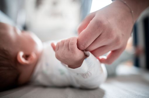 Ein Baby klammert sich an den Finger seiner Mutter. Foto: Fabian Strauch/dpa
