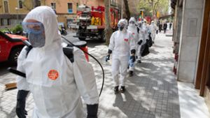 Barcelona: Soldaten in Schutzanzügen gehen mit Abstand in Richtung eines Seniorenheims, wo sie Desinfektionsmaßnahmen durchführen sollen. Foto: dpa/David Zorrakino