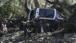 Einsatzkräfte des Los Angeles County Fire Department sind in Montecito, Kalifornien, USA, neben einem in Schutt und Schlamm liegenden Fahrzeug im Einsatz. Foto: AP