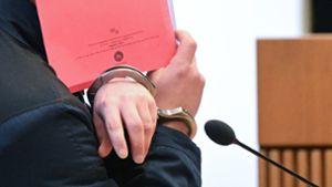 Der Angeklagte verdeckt sein Gesicht beim Betreten des Gerichtssaals. Foto: dpa/Bernd Weißbrod