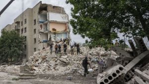 Rettungskräfte stehen auf den Trümmern eines Wohnblocks nach einem Raketeneinschlag in der Region Donezk in der Ostukraine. Foto: dpa/Nariman El-Mofty