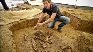 Grabungsleiter Jonathan Scheschkewitz zeigt das 6000 Jahre alte, ausgegrabene Skelett. Links ist die Grabbeigabe, eine geschliffene Steinbeilklinge, zu erkennen. Klicken Sie sich durch unsere Bildergalerie. Foto: Peter-Michael Petsch