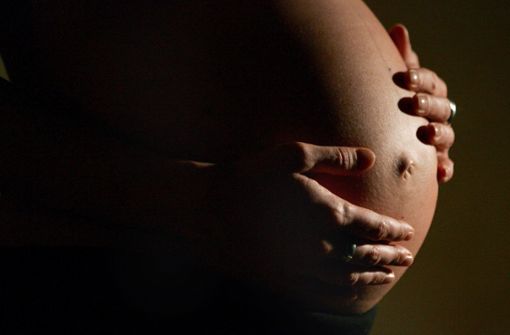 Eine hochschwangere Frau fasst sich mit beiden Händen an ihren Bauch. Auch Nicht-Trinker leiden in vielen Fällen unter den Folgen von Alkoholkonsum: So schädigen trinkende Mütter ihre ungeborenen Kinder. Foto: dpa